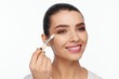 © Andriy Goncharenko - Portrait of a beautiful smiling young woman holding in her hand a white brush for makeup correction