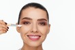 © Andriy Goncharenko - Portrait of a beautiful smiling young woman holding in her hand a white brush for makeup correction