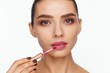© Andriy Goncharenko - Portrait of a beautiful young woman putting lipstick on her lips