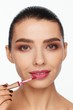 © Andriy Goncharenko - Portrait of a beautiful young woman putting lipstick on her lips
