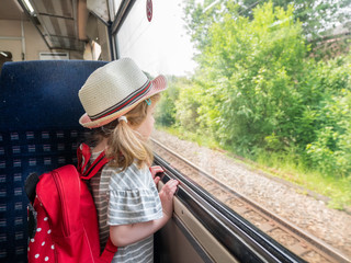 Young three year old girl looking out of a train window, London, UK