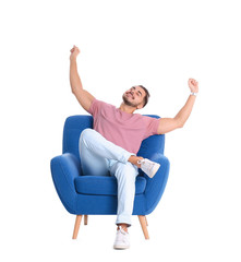 Wall Mural - Emotional young man sitting in armchair on white background