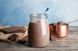 Jar with tasty chocolate milk on wooden table. Dairy drink