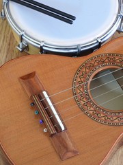 Close-up of two Brazilian musical instruments: cavaquinho and tamborim with drumstick on a wooden surface. They are widely used to accompany samba, the most popular Brazilian rhythm.