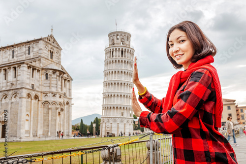 Fotomural Young woman traveler making funny poses in front of the famous leaning tower in Pisa, Italy