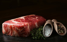A Piece Of Fresh Marbled Beef On A Wooden Background, With Spices For Cooking Steak
