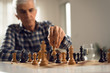 © Goran - Close up of senior man playing chess at home