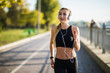 © dianagrytsku - Young beautiful fitness sport woman listening music running jogging in city street