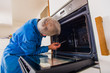 © qunica.com - Mature workman fixing oven