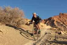 A Young Man Rides A Mountain Bike Down A Dirt Trail In The Desert Of Southern Utah On A Winter Day.