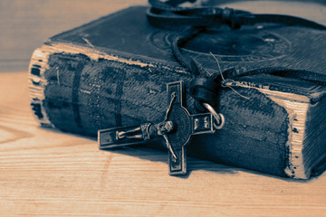 Crucifix necklace on a bible with wood background with colour toning