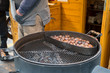 Street food market. Roasting brown chestnuts in a big pot.