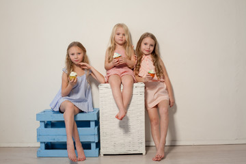 three little girls eat sweet cake with cream cupcake