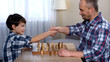 © motortion - Male kid winning chess with his father, little son shaking hand with dad, hobby