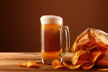 Wall Mural - Close up beer glass and potato chips over brown