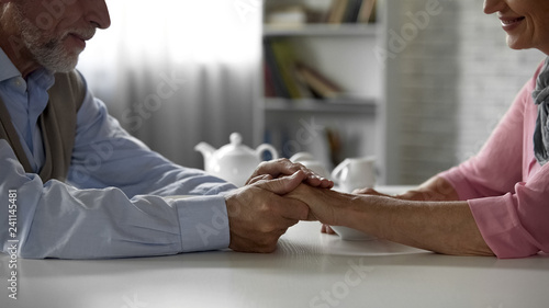 Fotografía Retiree husband holding tenderly wifes hand, having tea together, happiness