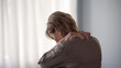 © motortion - Elderly lady suffering spine ache, standing backwards rubbing neck and shoulders