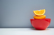 healthy freshness juicy slice and half cut of orange fruit for food in red ceramic bowl on white table with gray background