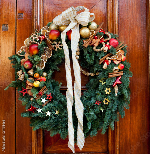 Fotografie, Obraz Fabulous outdoor Christmas wreath ornamented with artificial fruit against woode