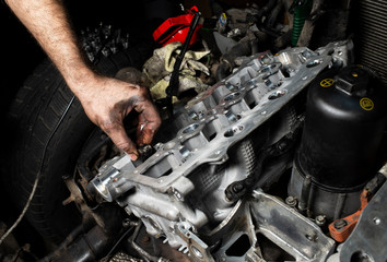 Mechanic hand checking and fixing a broken car in car service garage