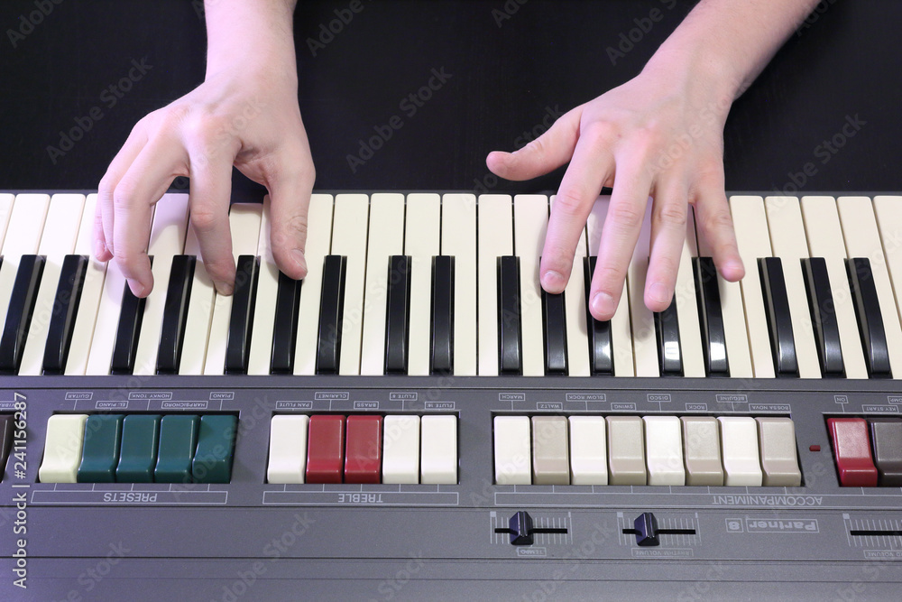 A right hand playing a G# sharp (SOL#) minor chord on an old black piano with yellowed cracked keys, pressing the G# sharp (SOL#), B (SI), D# sharp (RE#) notes - obrazy, fototapety, plakaty 