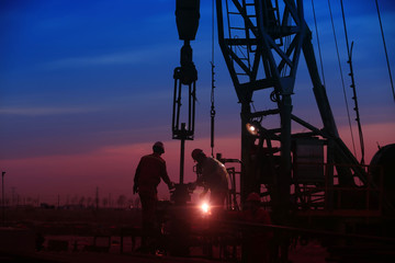 Oil workers work in the evening at the oil field