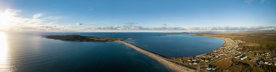 Aerial panoramic view of a small town on the Atlantic Ocean Coast during a vibrant sunny sunset. Taken in Cow Head, Newfoundland, Canada.