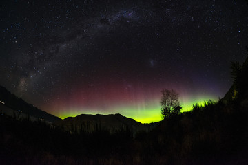 spectacular view as aurora lights up the sky of queenstown, new zealand. when particles from a solar