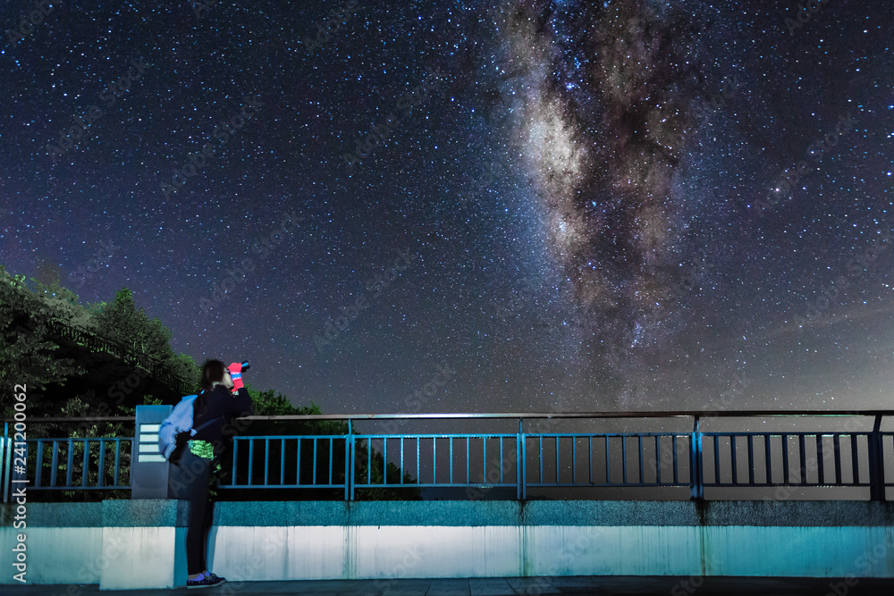 Young girl looks up at the night sky and milky way galaxy with ...