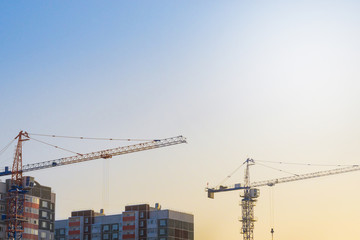 two cranes building a house