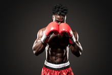 Muscular African American Black Male Sweaty Boxer Covers His Head As He Comes  Towards The Camera  With Dramatic Lighting With A Black Background  