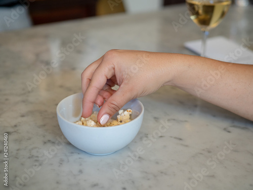 Valokuva Woman manicured hand inside a small bowl of popcorn with wine
