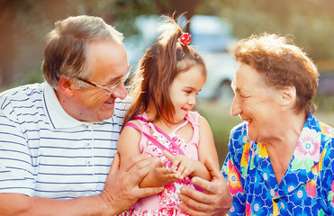 Wall Mural - Family, generation and people concept - happy smiling grandmother, grandfather and little granddaughter at park