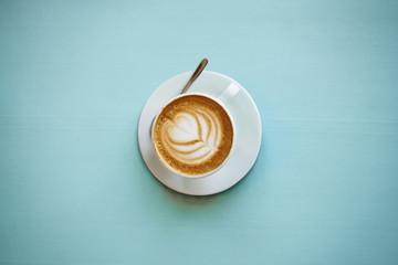 Wall Mural - A cup with a traditional tasty and aromatic morning cappuccino on a blue background.