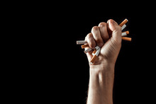 Creative Background, Male Hand Clenches A Fist Of A Cigarette. The Concept Of Smoking Kills, Stop Smoking. Copy Space.