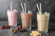 Glasses with different protein shakes and ingredients on table against grey background
