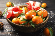 Bowl with ripe tangerines, Christmas gifts and artificial snow on wooden table