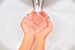 Female hands under running water in the sink