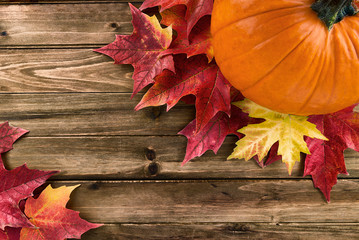 Pumpkin with red maple leafs disposed on wooden table. Flat lay, top view fall autumn concept.