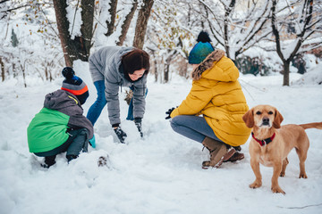 Wall Mural - Family with a dog playing in the snow