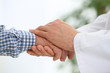 © New Africa - Doctor holding elderly patient hand on blurred background, closeup