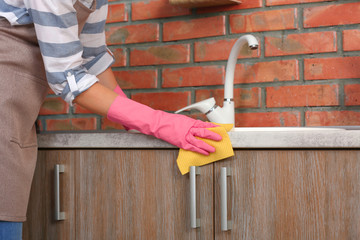 Wall Mural - Woman cleaning kitchen counter with rag, closeup