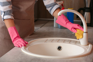 Wall Mural - Woman cleaning tap with rag in kitchen, closeup