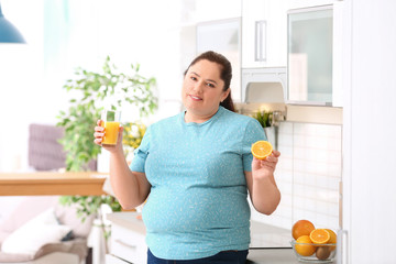 Sticker - Overweight woman with glass of fresh juice and orange in kitchen. Healthy diet