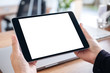 © Farknot Architect - Mockup image of hands holding and using black tablet pc with blank white desktop screen with notebook on wooden table in office