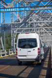 Fototapeta Miasto - Compact cargo mini van for small business and delivery running on silver truss bridge