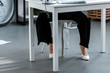 © LIGHTFIELD STUDIOS - cropped view of woman in white shoes and trousers sitting at table at workplace