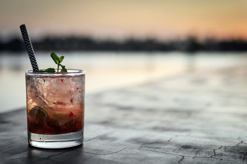 strawberry caipirinha mixed cocktail drink in outdoor bar at sunset