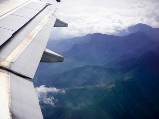 Airplane Wing Flying over Mountains with Jungle