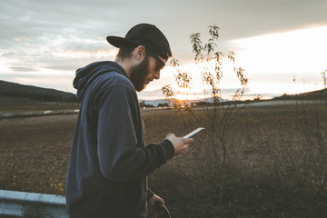 Guy with sunglasses and cap looking at the mobile phone.People watching the cell phone